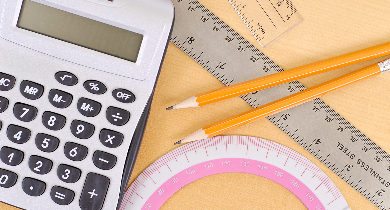 Une calculatrice, des règles et des crayons sur un bureau