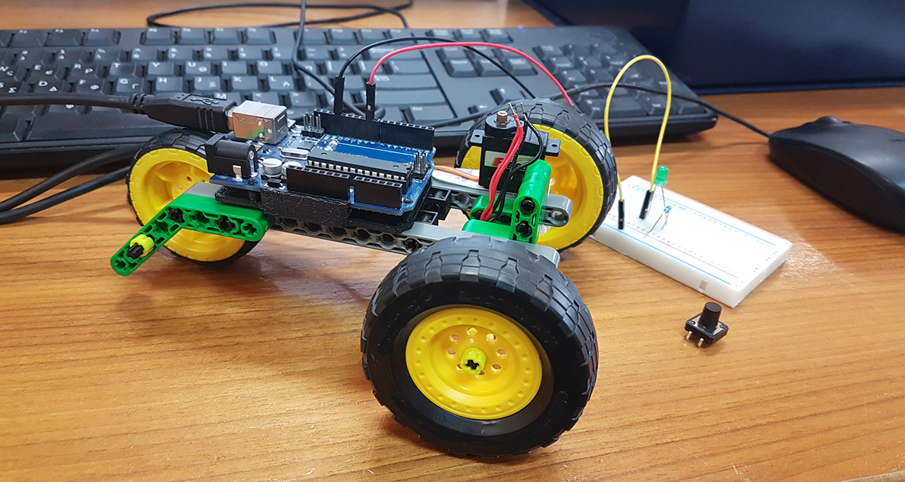 A small robotic tractor sits on a desk